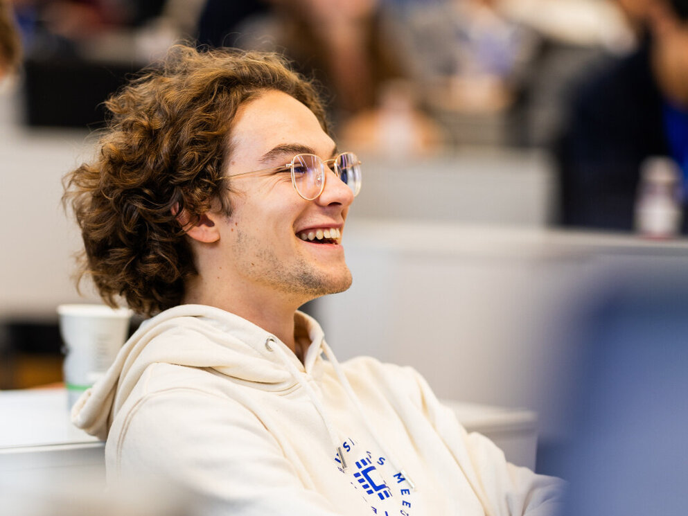 Ein lächelnder Student nimmt an einer Vorlesung zum Thema Finanzmanagement teil.
