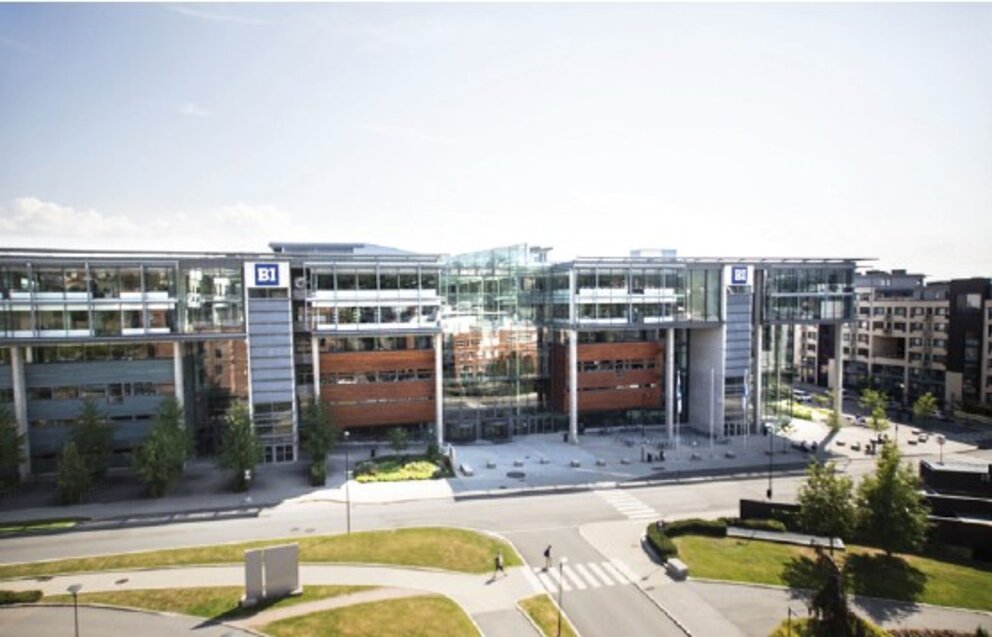 Ein Blick aus der Luft auf die BI Norwegian Business School, ein modernes Gebäude aus Stahl und Glas mit Flachdach.