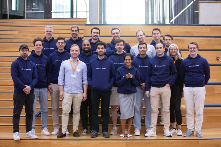 A group of around twenty people mostly wearing navy hoodies with the WHU Accelerator logo pose for the camera on some steps.
